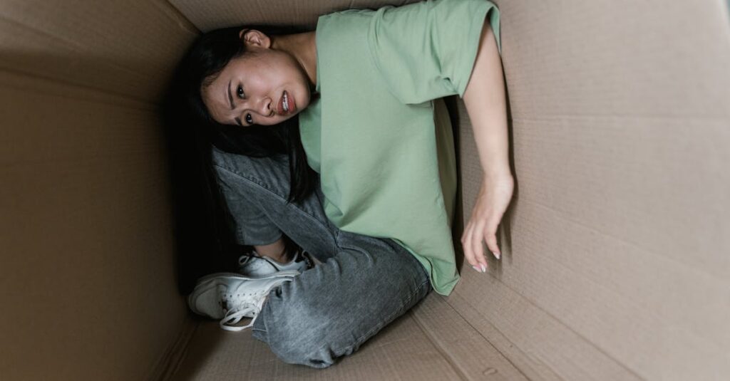 A woman trapped inside a cardboard box, symbolizing anxiety and fear.