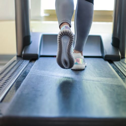 Close-up shot of a person exercising on a treadmill, showcasing fitness and health focus.
